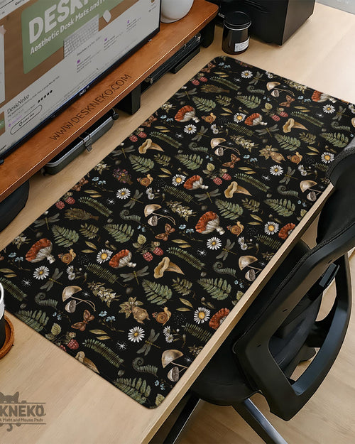 Black desk mat with a dark academia botanical pattern featuring mushrooms, insects, and forest foliage.
