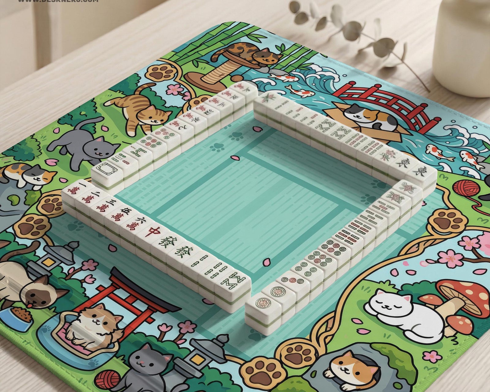 Mint green square mahjong mat with a Japanese garden style border featuring cats, koi fish, bamboo, blossoms, and small scenic details.