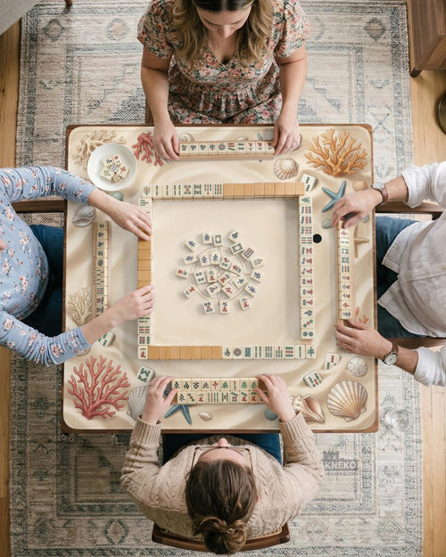 A rectangular mahjong table mat with a neutral coastal design featuring seashells, coral, and starfish around a blank center.
