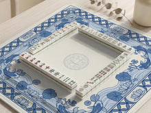 Blue and white square mahjong table mat with koi fish, lotus flowers, water lilies, and flowing wave patterns around a plain center.