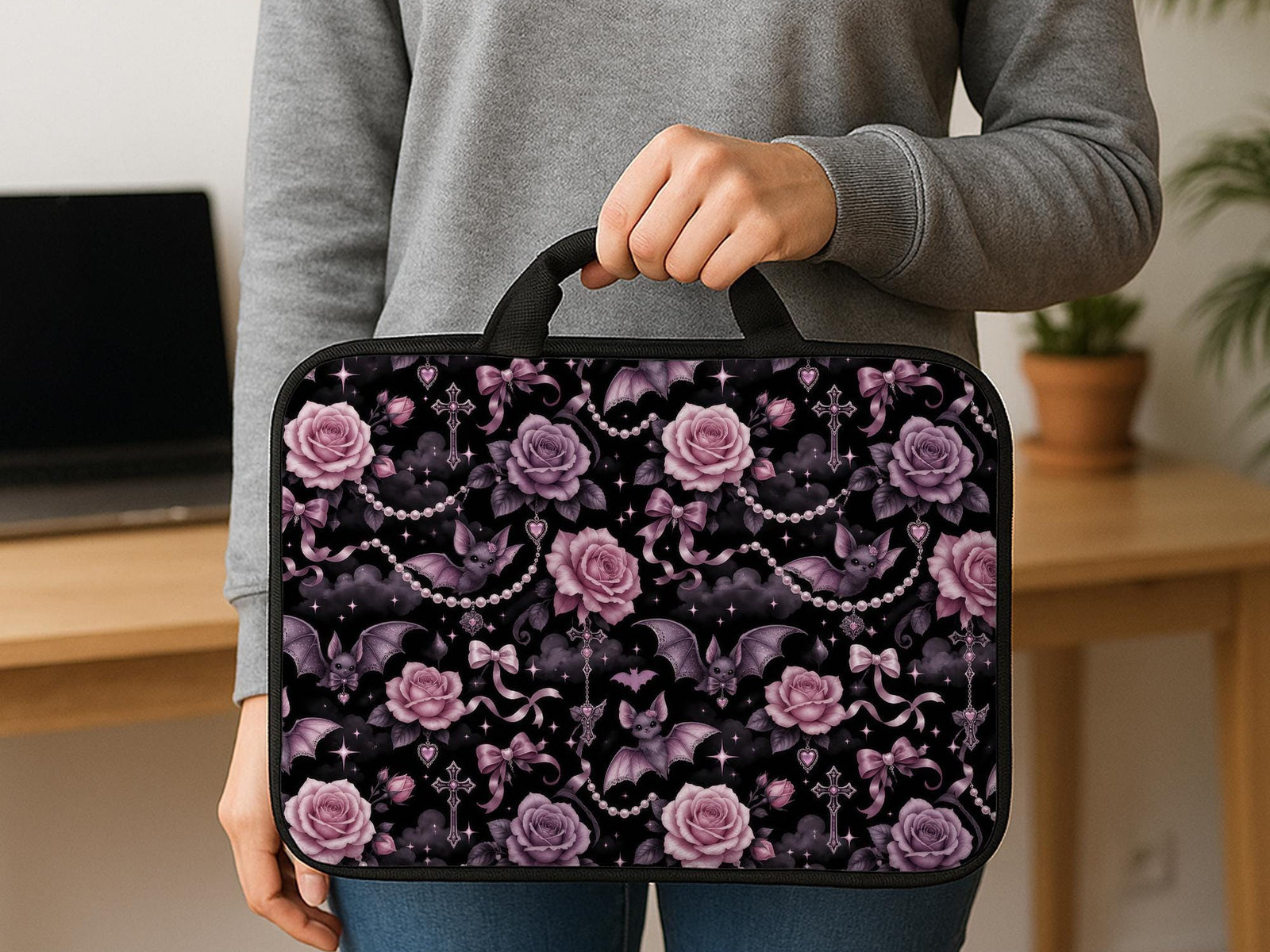 Pink laptop sleeve case with pastel goth print showing roses, small bats, bows, pearl chains, smoky clouds, and sparkle details.