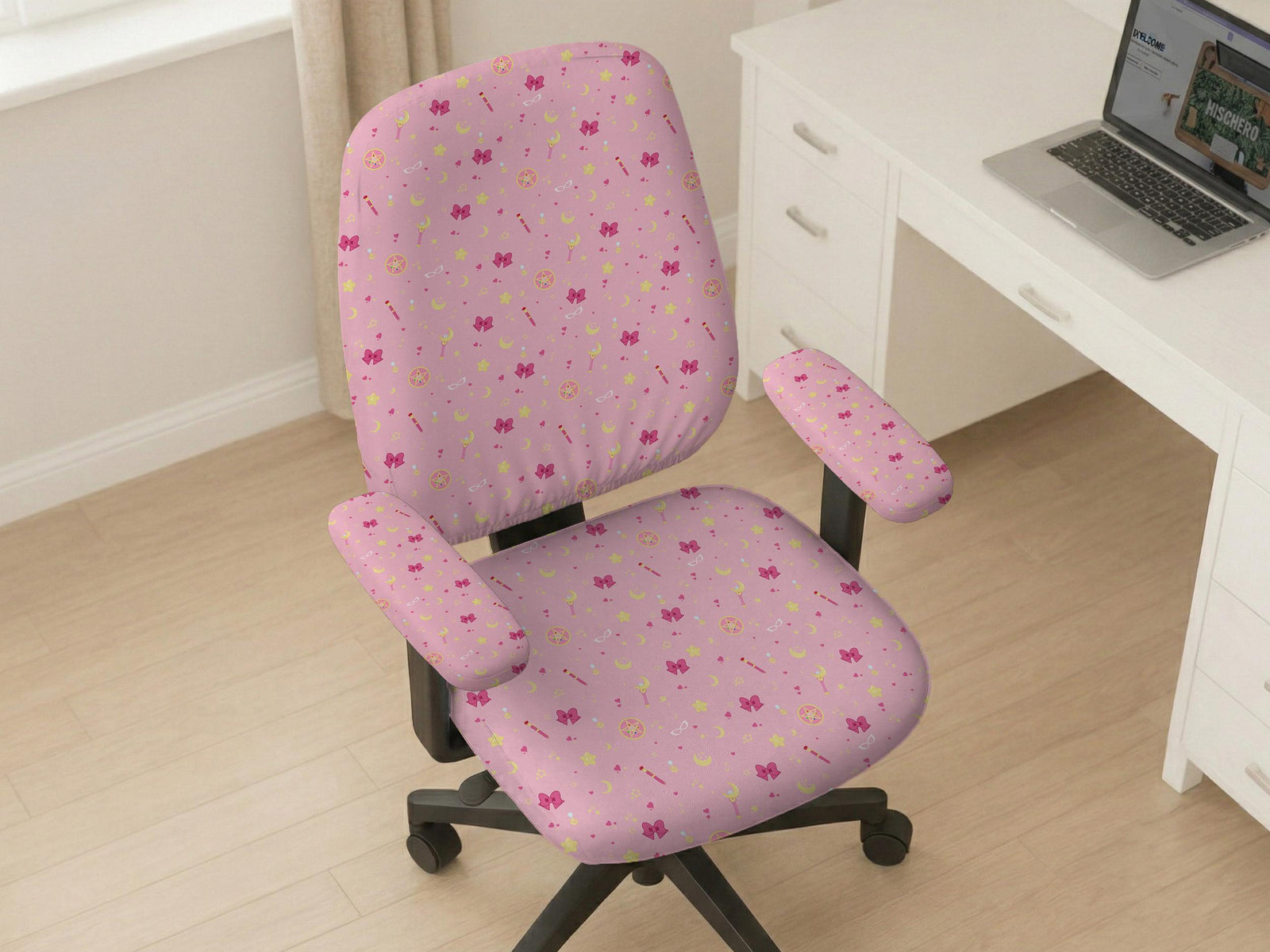 Pink chair cover with a pattern of moons, stars, bows, and small decorative shapes on a chair with armrests.
