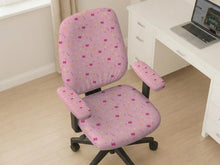 Pink chair cover with a pattern of moons, stars, bows, and small decorative shapes on a chair with armrests.
