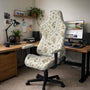 A chair cover with a creamy background and pastel meadow floral print shown on a high back office or gaming chair.