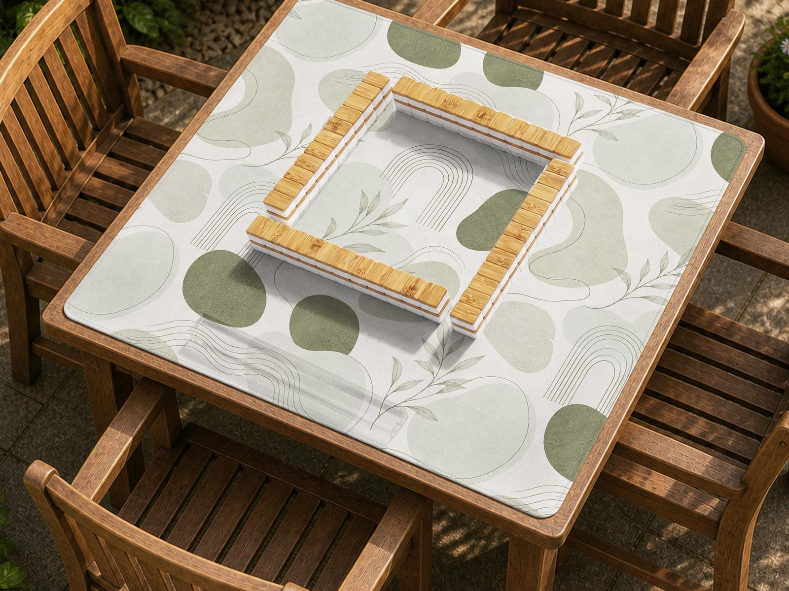 Square mahjong table mat with a sage green botanical design, abstract leaf shapes, and a soft neutral background.