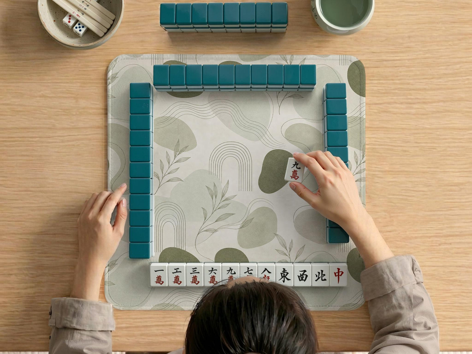 A square sage green mahjong mat with a botanical leaf pattern, fine line details, and a minimalist design.