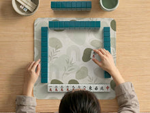 A square sage green mahjong mat with a botanical leaf pattern, fine line details, and a minimalist design.