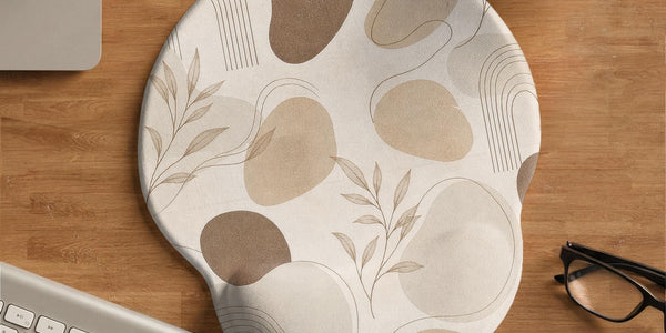 Beige ergonomic mouse pad with a neutral abstract botanical pattern and a raised wrist support area on one side.