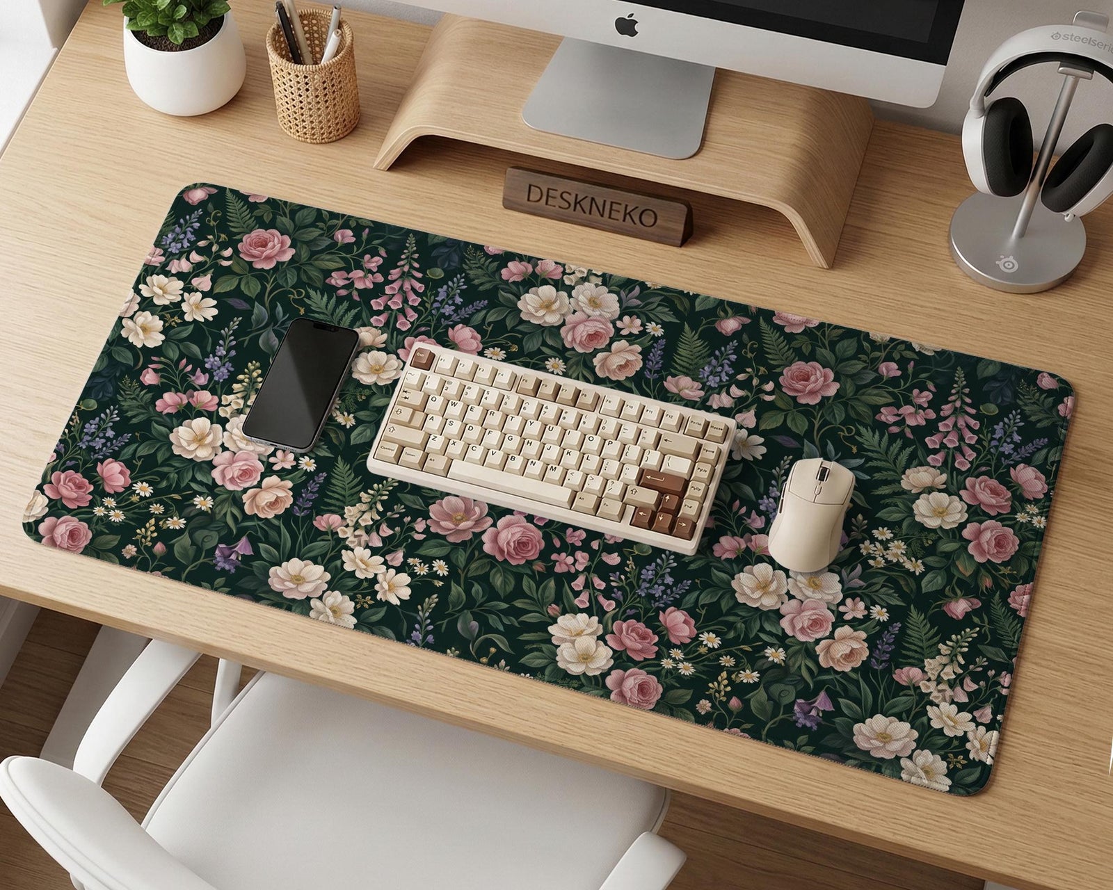 A dark green desk mat with an all-over vintage floral pattern of blush roses, cream flowers, small daisies, and leafy ferns.