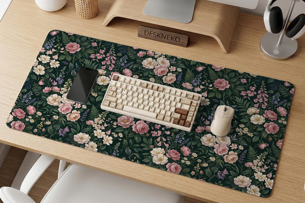 A dark green desk mat with an all-over vintage floral pattern of blush roses, cream flowers, small daisies, and leafy ferns.