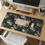 A dark green desk mat with an all-over vintage floral pattern of blush roses, cream flowers, small daisies, and leafy ferns.