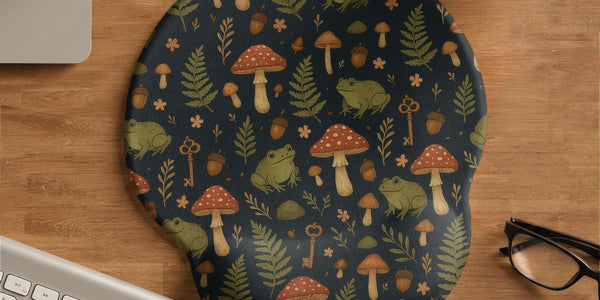 Mouse pad with a green frog, red mushrooms, fern leaves, tiny flowers, acorns, and old key details in a woodland pattern.