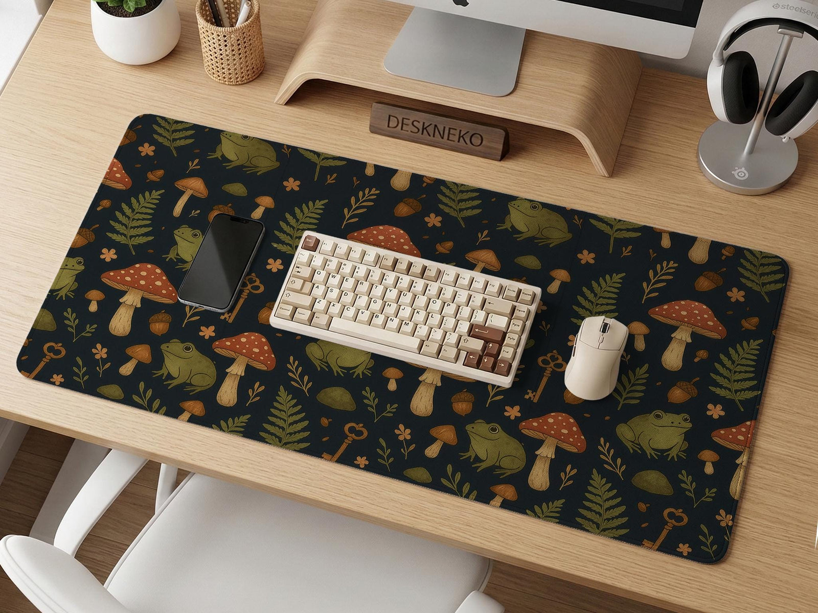 Dark botanical desk mat with an all-over pattern of frogs, mushrooms, fern leaves, acorns, tiny flowers, and antique key details.