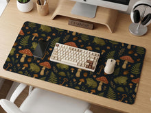 Dark botanical desk mat with an all-over pattern of frogs, mushrooms, fern leaves, acorns, tiny flowers, and antique key details.