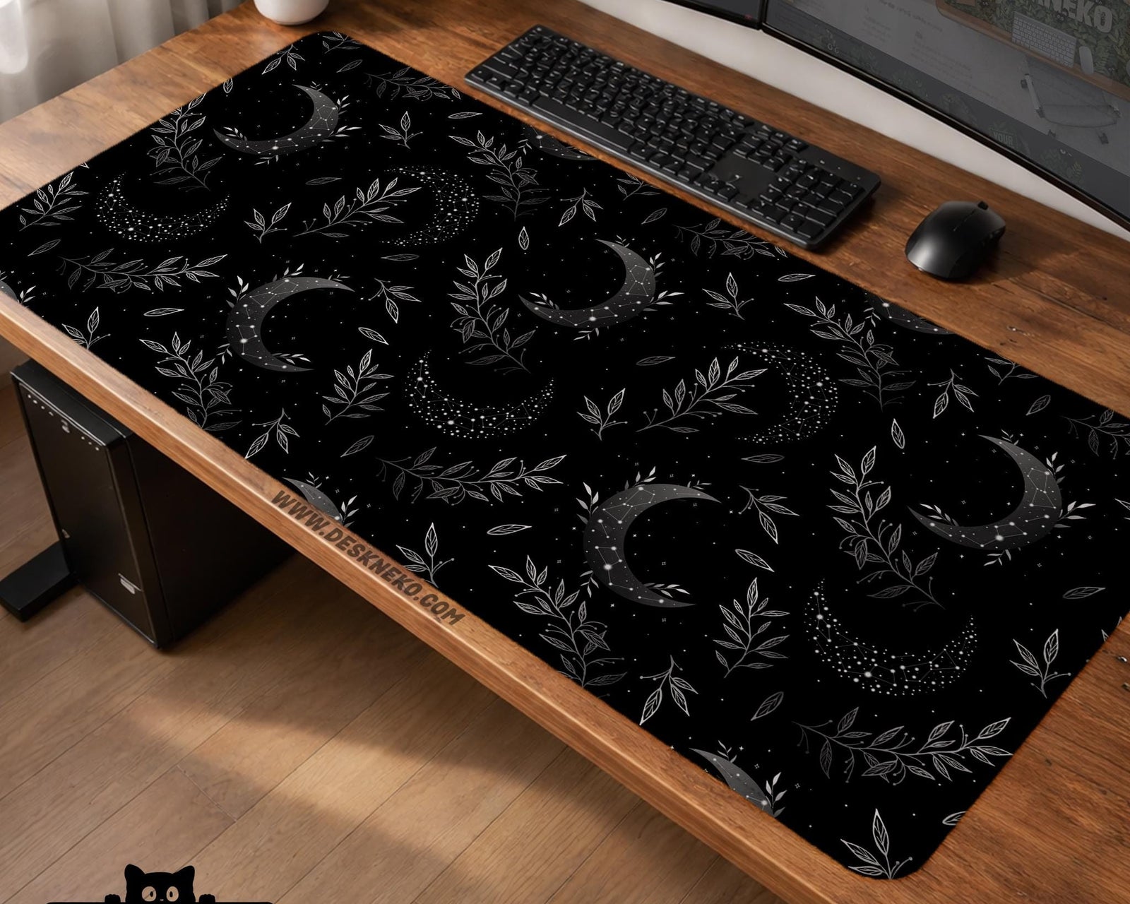 A black desk mat with a crescent moon, scattered stars, and leafy botanical branches in a celestial pattern.