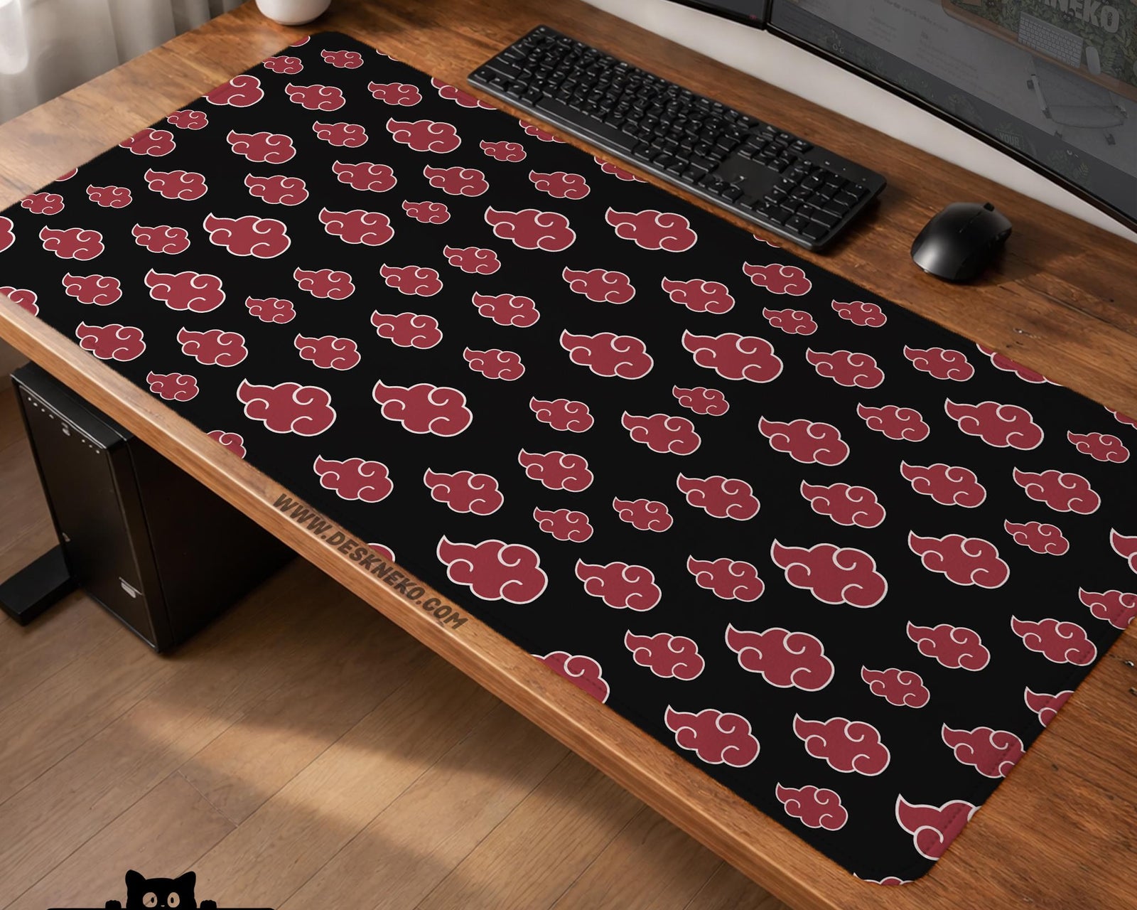 A black desk mat with a red cloud pattern shown on a computer desk with a keyboard and mouse.