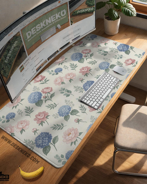 Floral desk mat with sage greenery, pink peonies, blue flowers, and a warm cream background.