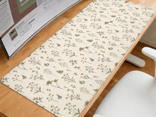 Desk mat with a sage green background, tiny wildflowers, and a vintage botanical floral pattern.