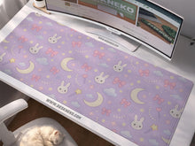 Lavender desk mat with an all-over pattern of bunny faces, clouds, moons, bows, and flowers in pastel colors.