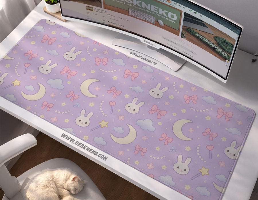 Lavender desk mat with an all-over pattern of bunny faces, clouds, moons, bows, and flowers in pastel colors.
