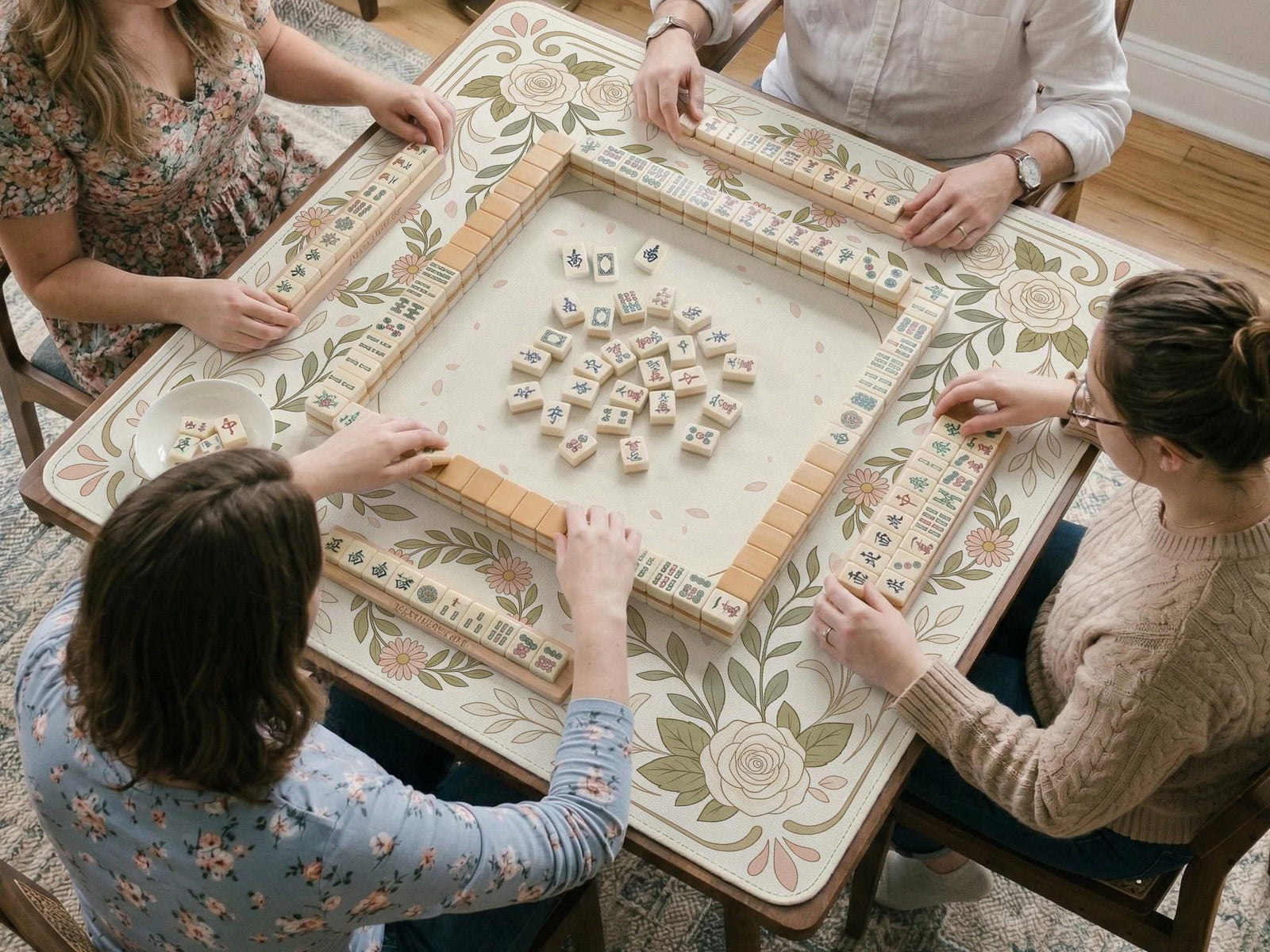 Square mahjong mat with a light floral border in sage green, cream, and blush around a plain center play area.
