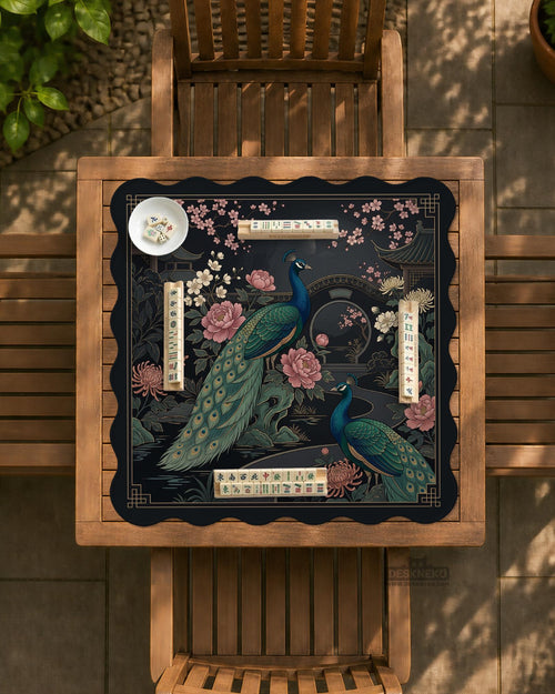 Square black mahjong mat with a gold peacock, blush flowers, and dark botanical artwork on a dark background.