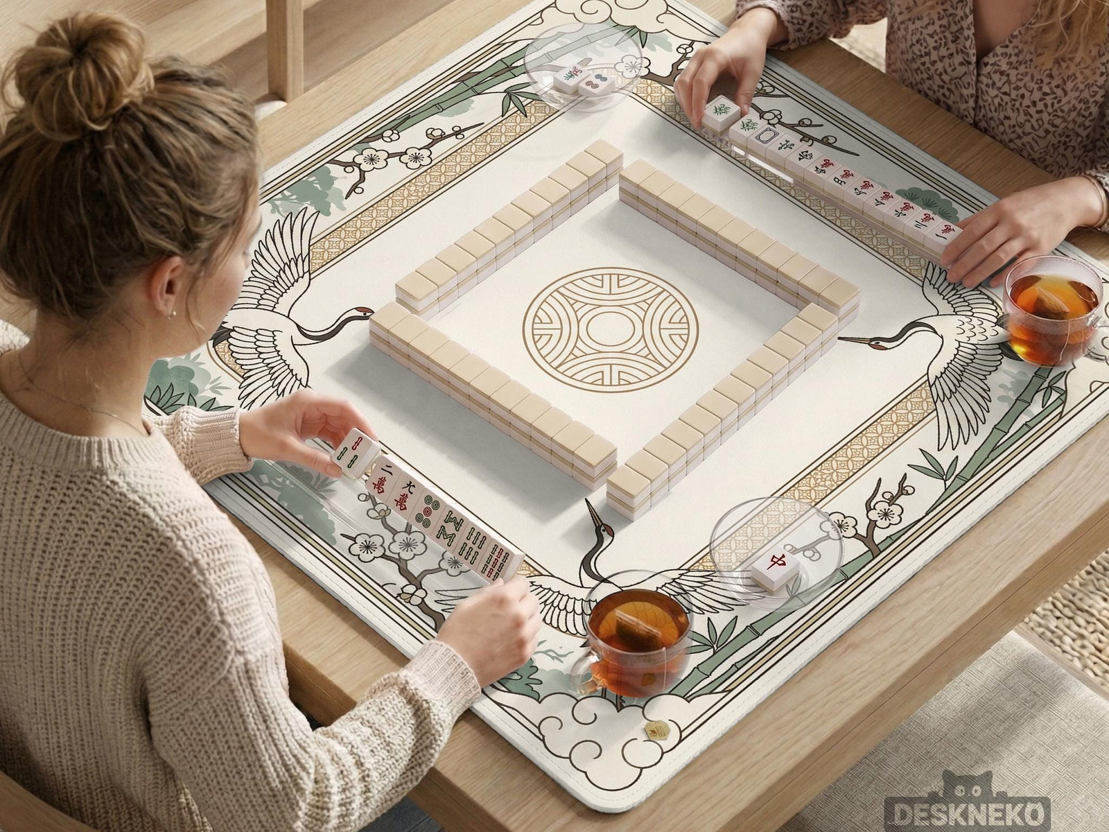A square cream and sage mahjong mat with a crane, bamboo, blossoms, and a thin gold border.