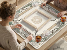 A square cream and sage mahjong mat with a crane, bamboo, blossoms, and a thin gold border.