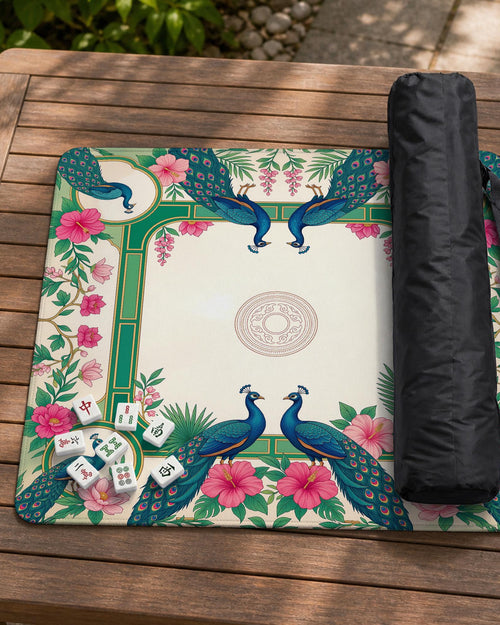 A square mahjong mat with teal peacocks, pink hibiscus flowers, green borders, cream open space, and gold accents.
