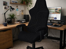 Black chair cover with a thin line art pattern on a gaming chair, shown with a high back and armrest areas covered.