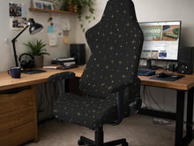 Black stretch chair cover with small gold star pattern, shown on a high-back chair with armrests.