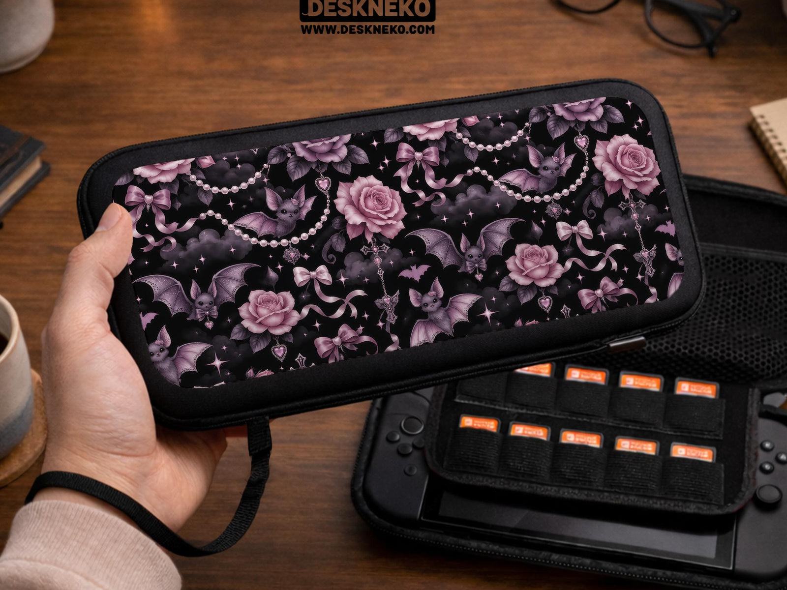 A black Switch carrying case with a pink gothic rose print, small bats, ribbon bows, pearl chain details, and tiny sparkles.