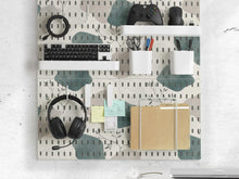 Four pegboard panels in sage green with cream, grey, teal, and leafy botanical artwork arranged in a square layout.