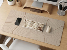Beige desk mat with soft brown topographic contour lines on a neutral background.