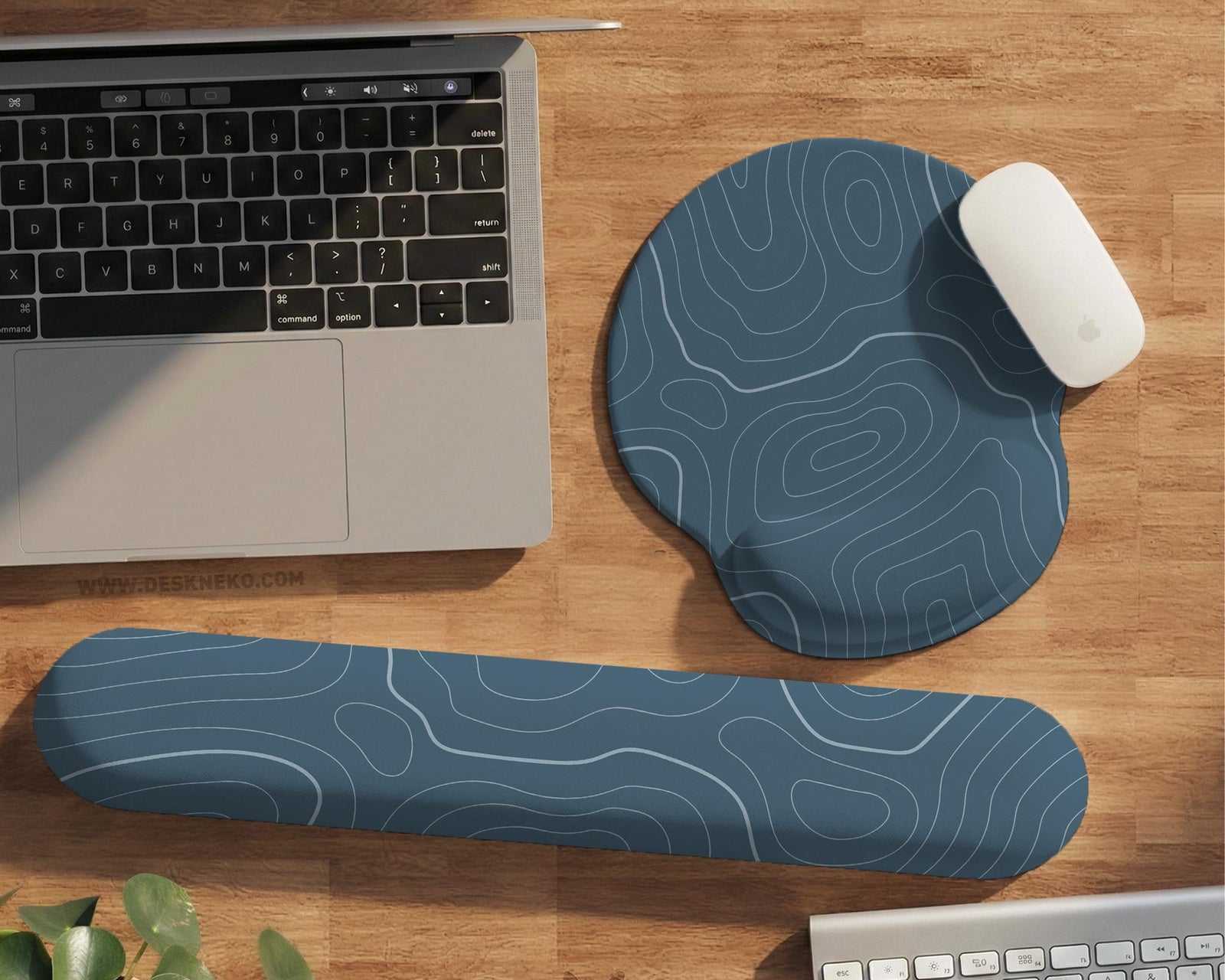 Muted blue desk mat with thin topographic line art pattern shown with matching mousepad and keyboard wrist rest options.