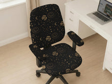 Black chair cover with a dark galaxy pattern, muted gold stars and celestial artwork on a chair.