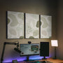 Three sage acoustic wall panels with an abstract design, curved linework, and small botanical details arranged in a triptych layout.