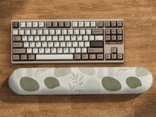 Sage green desk mat and wrist rest design with abstract botanical shapes and fine line details on a light background.