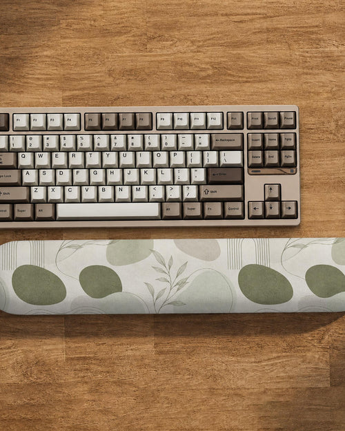 Sage green desk mat and wrist rest design with abstract botanical shapes and fine line details on a light background.