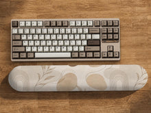 Cream desk set with a botanical pattern, fine line abstract shapes, a matching mousepad, and a long keyboard wrist rest.