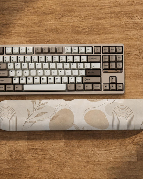 Cream desk set with a botanical pattern, fine line abstract shapes, a matching mousepad, and a long keyboard wrist rest.
