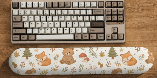 Cream mouse pad and keyboard wrist rest with a woodland pattern featuring foxes, bunnies, bears, mushrooms, acorns, and leaves.