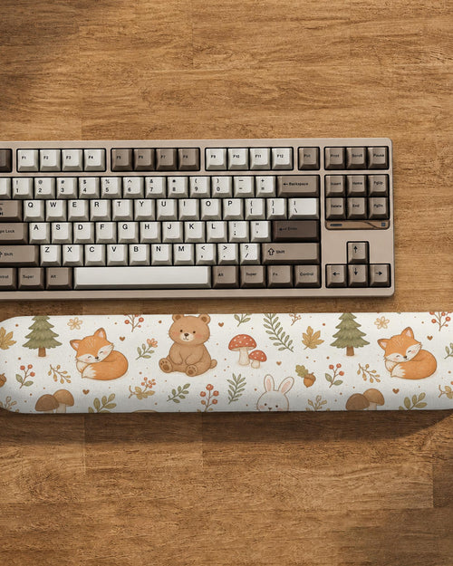 Cream mouse pad and keyboard wrist rest with a woodland pattern featuring foxes, bunnies, bears, mushrooms, acorns, and leaves.