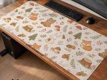 Cream desk mat with a woodland animal pattern featuring foxes, bunnies, mushrooms, berries, acorns, and sage leaves in soft green tones.