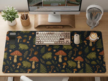 Dark forest-themed desk mat with an all-over pattern of frogs, mushrooms, fern leaves, acorns, tiny flowers, and antique keys.