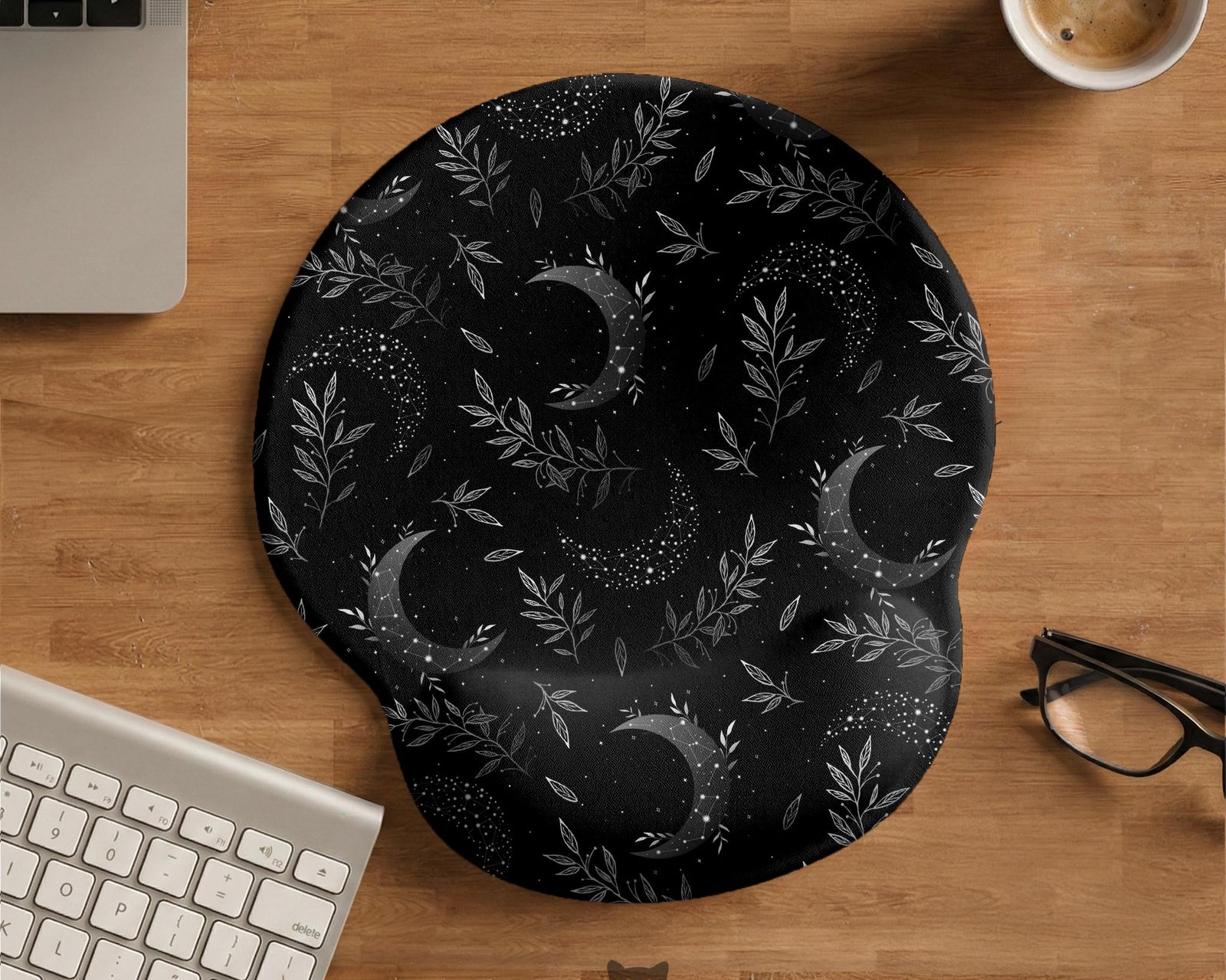 Black mouse pad and wrist rest with moon phases, small stars, and fine botanical accents in a dark floral pattern.