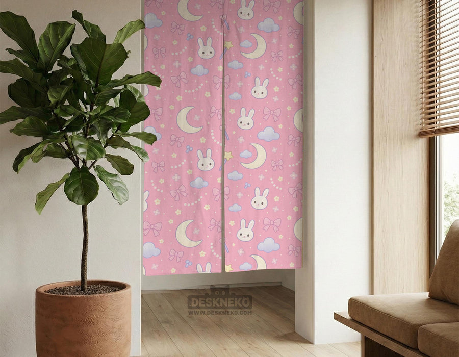 Pink noren curtain with cute bunny faces, crescent moons, blue clouds, bows, stars, and small flowers on a warm pink background.