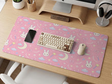 Pink desk mat with a kawaii design featuring bunnies, clouds, moons, bows, flowers, and a small magic wand pattern.