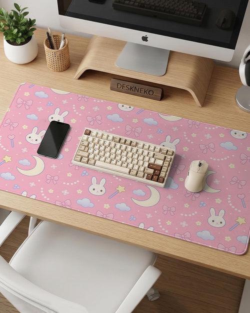 Pink desk mat with a kawaii design featuring bunnies, clouds, moons, bows, flowers, and a small magic wand pattern.