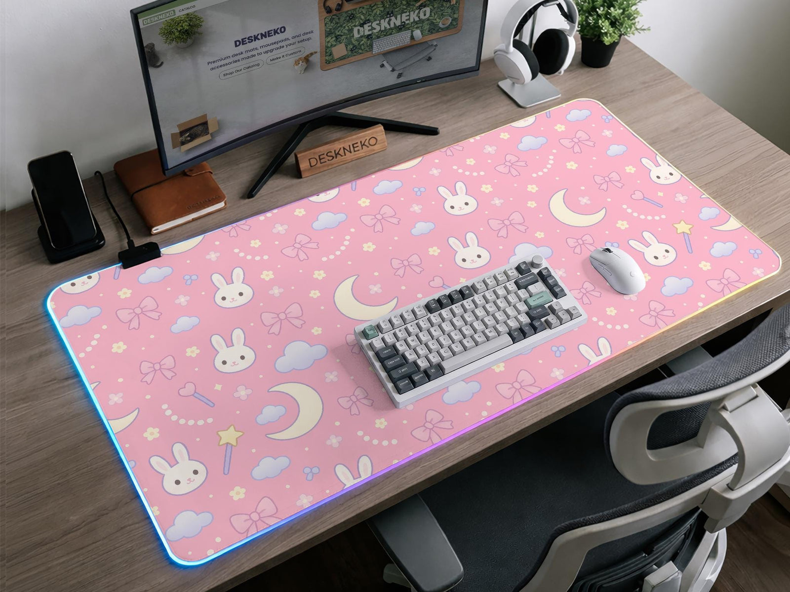 Pink desk mat with pastel bunnies, moons, clouds, bows, and stars on a light background.